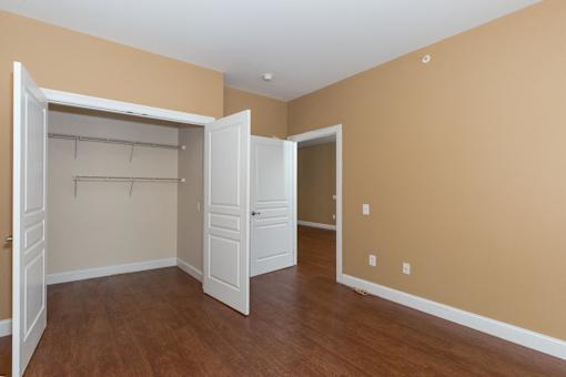 A room with a white closet and wooden floors.