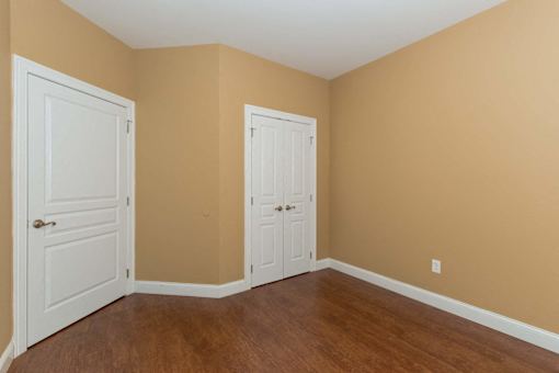 A room with two white doors and wooden floors.