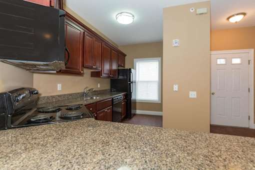 A kitchen with granite countertops and wooden cabinets.