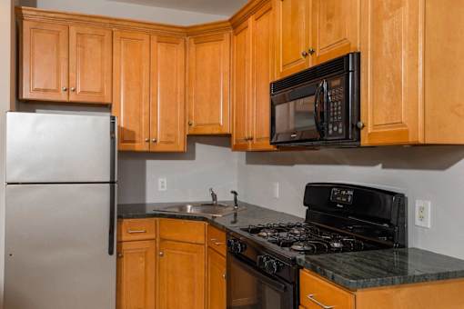 A kitchen with wooden cabinets and a black microwave above the stove.