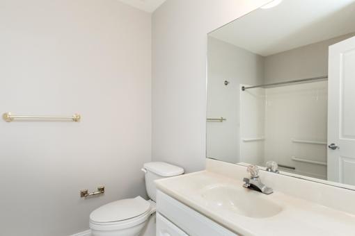 A white bathroom with a toilet, sink, and mirror.