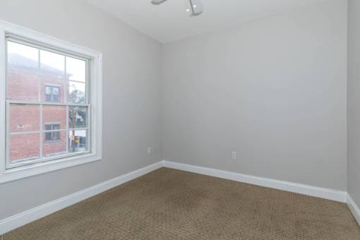 A room with a window and carpeted floor.
