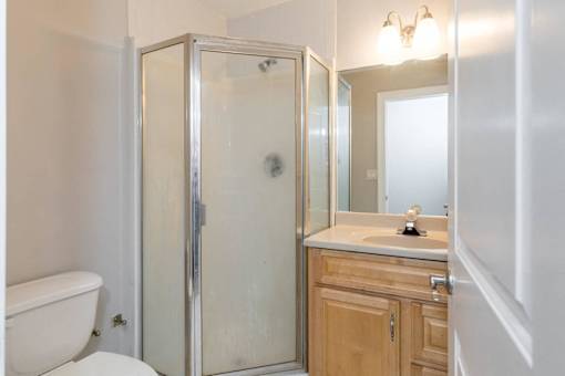 A white bathroom with a toilet, sink, and shower.