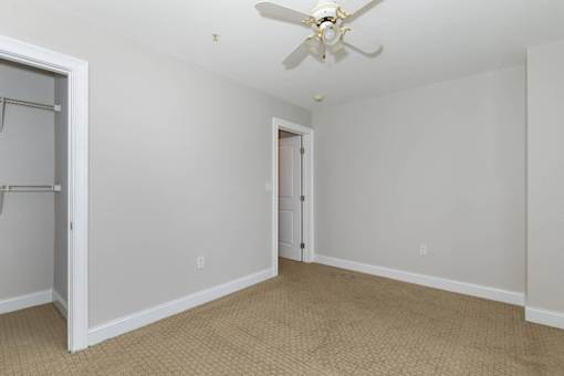 A room with a ceiling fan and carpeted floor.