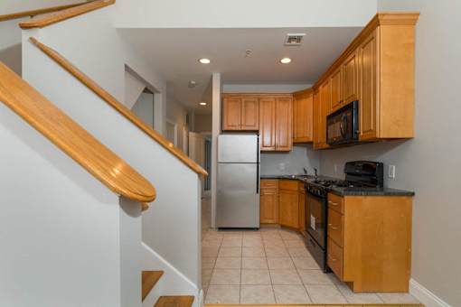 A kitchen with wooden cabinets and a stainless steel refrigerator.