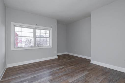 A room with a window and wooden flooring.