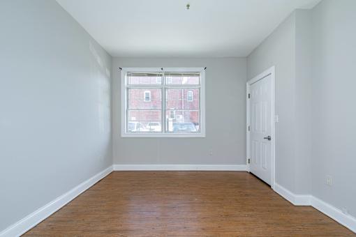 Empty room with a window and wooden floor.