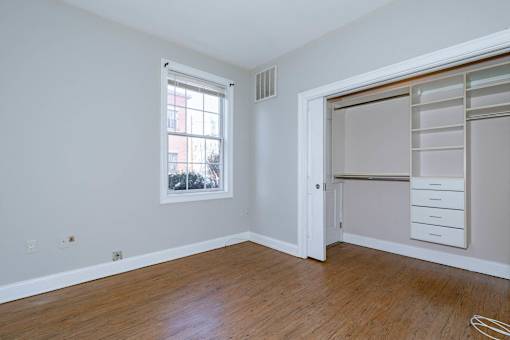 A room with a window and a door with a shelf.