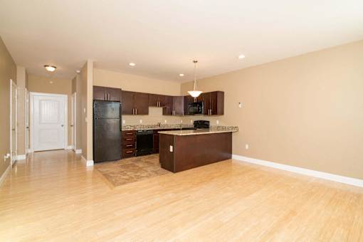 A kitchen with a black refrigerator and wooden floors.