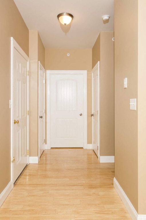 A long hallway with a white door at the end.