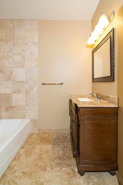 A bathroom with a tiled shower and a wooden cabinet.