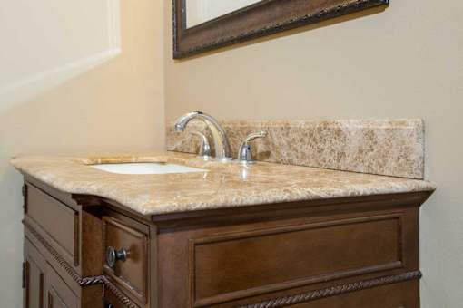 A bathroom vanity with a marble countertop and a mirror above it.