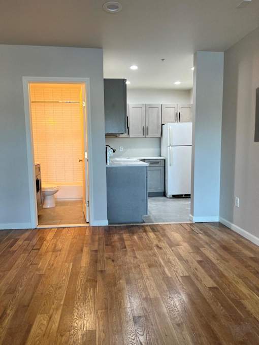 A kitchen with a white refrigerator and wooden floors.