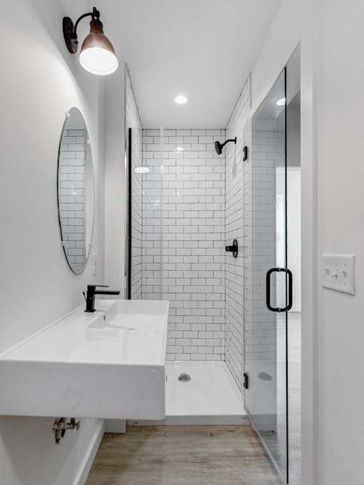 A white sink in a modern bathroom with a glass shower door.