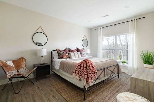 A bedroom with a bed, chair, and a rug.