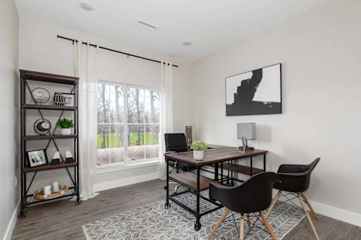 A black and white photo is hanging on a white wall above a wooden table.