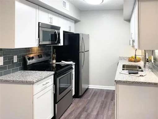 A kitchen with black appliances and white cabinets. at Latitude at Riverchase, Hoover, AL, 35216