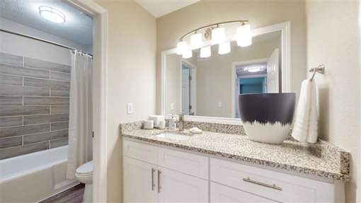 A bathroom with a marble countertop and a large mirror. at Vinings RiverVue, Georgia