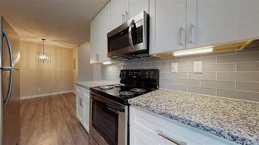 A kitchen with a black microwave above the stove. at Vue on Medlock, Peachtree Corners, GA, 30092