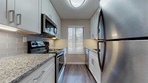 A kitchen with a stove top oven and a microwave above it. at Vue on Medlock, Peachtree Corners, Georgia