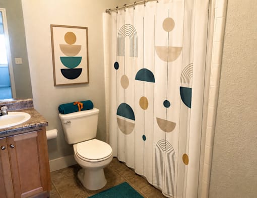 A bathroom with a toilet, sink, and shower curtain.