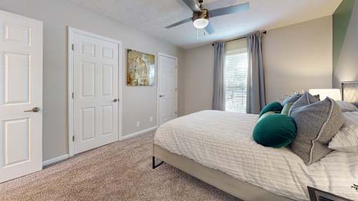 A bedroom with a bed, pillows, and a ceiling fan.