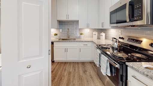 A modern kitchen with white cabinets and a black stove top.