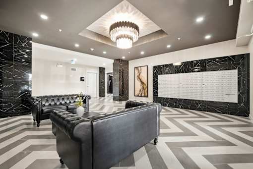 A black and white checkered floor in a spacious room with a large couch and a chandelier.