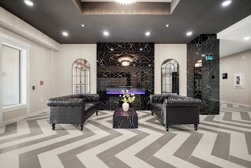 A room with a black and white chevron carpet and two black leather ottomans.