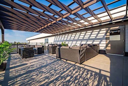 A patio with a wooden roof and furniture.
