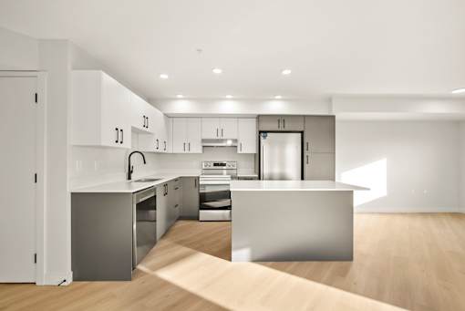 A modern kitchen with a wooden floor and white walls.