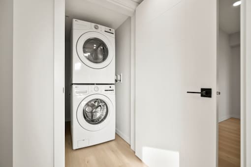 A white washing machine is in a small, white-walled room.