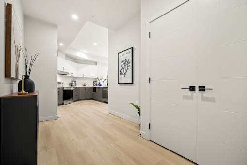 A modern kitchen with a white door and a wooden floor.