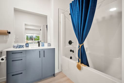 A white bathroom with a blue shower curtain.