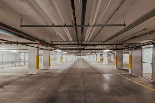 A long, empty parking garage with yellow poles and white walls.