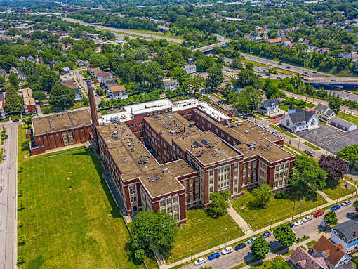 An aerial view of a large red brick building with a green lawn in front.