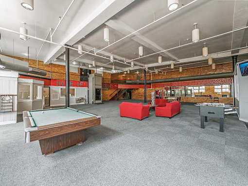 A billiard table is in the middle of a room with a pool table and a foosball table.