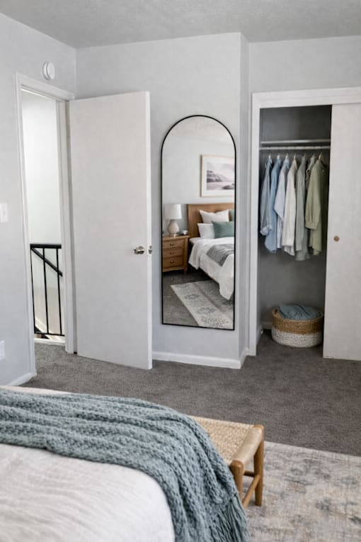 A bedroom with a bed, a wardrobe, and a mirror.