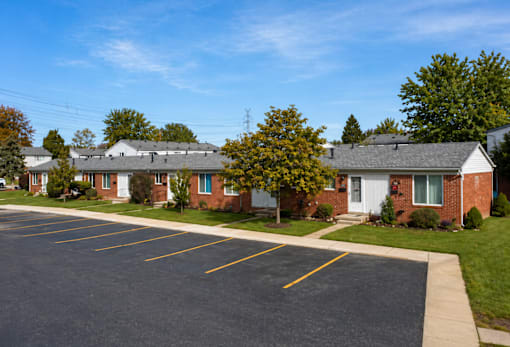 A parking lot in front of a brick building with a white door.