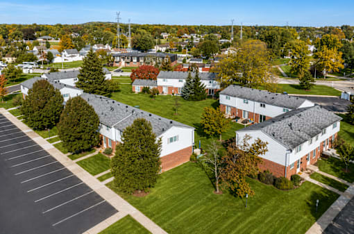 A parking lot is in the foreground of a residential area with houses and trees.