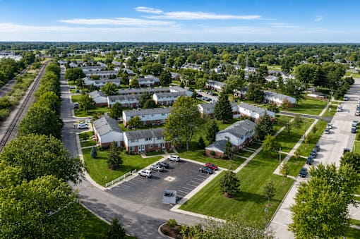 A bird's eye view of a residential area with houses, roads, and cars.
