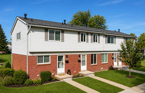 A two-story house with a red brick base and white siding.