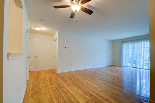 A room with a ceiling fan and wooden floors.