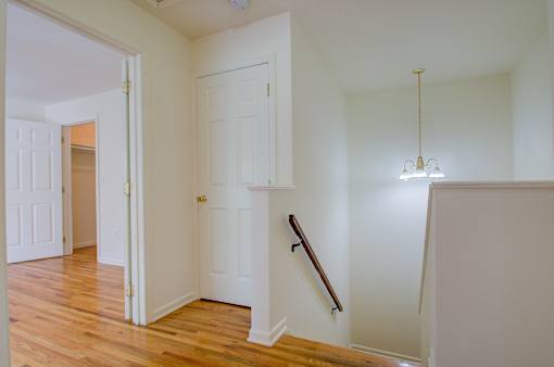 A white room with a wooden floor and a chandelier hanging from the ceiling.