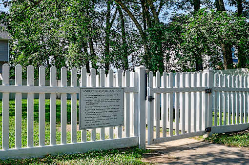 A white picket fence with a sign that says Andrew's Corner Dog Park.