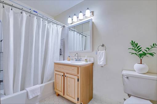 A bathroom with a wooden vanity and a white bathtub.