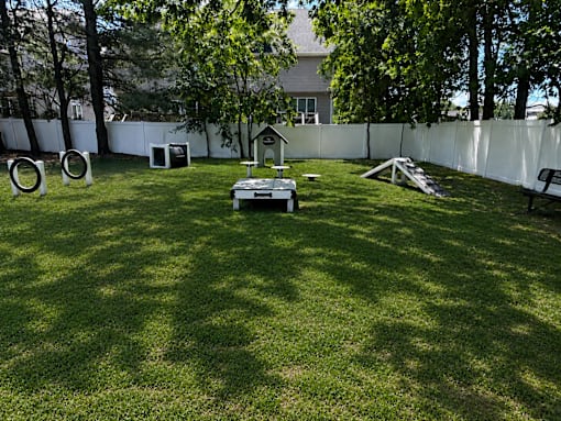 A backyard with a white fence and a dog house.