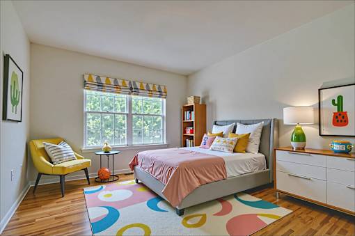 A bedroom with a bed, chair, and a rug.