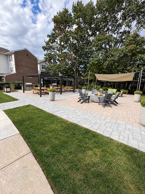 A patio with a table and chairs is surrounded by a grassy area.