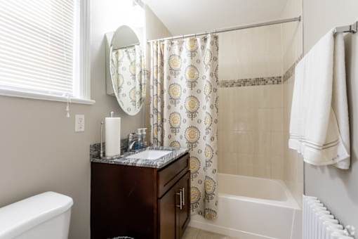 A bathroom with a white tub, a brown vanity, and a shower curtain.